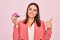 Young beautiful brunette business woman holding small car toy over pink background Smiling happy and positive, thumb up doing Royalty Free Stock Photo