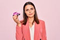 Young beautiful brunette business woman holding small car toy over pink background thinking attitude and sober expression looking Royalty Free Stock Photo