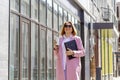 a young beautiful brunette businesswoman in sunglasses and a pink coat is walking along a city street Royalty Free Stock Photo