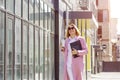 a young beautiful brunette businesswoman in sunglasses and a pink coat is walking along a city street Royalty Free Stock Photo