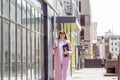 a young beautiful brunette businesswoman in sunglasses and a pink coat is walking along a city street Royalty Free Stock Photo