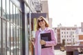 a young beautiful brunette businesswoman in sunglasses and a pink coat is walking along a city street Royalty Free Stock Photo
