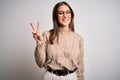 Young beautiful brunette businesswoman wearing casual sweater and glasses standing smiling with happy face winking at the camera Royalty Free Stock Photo