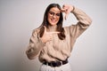 Young beautiful brunette businesswoman wearing casual sweater and glasses standing smiling making frame with hands and fingers Royalty Free Stock Photo