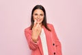 Young beautiful brunette businesswoman wearing elegant jacket over isolated pink background Beckoning come here gesture with hand