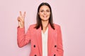 Young beautiful brunette businesswoman wearing elegant jacket over isolated pink background smiling looking to the camera showing Royalty Free Stock Photo