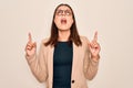 Young beautiful brunette businesswoman wearing jacket and glasses over white background amazed and surprised looking up and Royalty Free Stock Photo