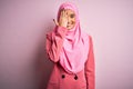 Young beautiful brunette businesswoman wearing pink muslim hijab and business jacket covering one eye with hand, confident smile Royalty Free Stock Photo