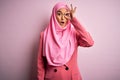 Young beautiful brunette businesswoman wearing pink muslim hijab and business jacket doing ok gesture shocked with surprised face, Royalty Free Stock Photo