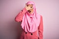 Young beautiful brunette businesswoman wearing pink muslim hijab and business jacket peeking in shock covering face and eyes with Royalty Free Stock Photo