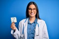 Young beautiful brunette doctor woman holding paper with question mark symbol message with a happy face standing and smiling with Royalty Free Stock Photo