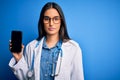 Young beautiful brunette doctor woman wearing glasses and coat holding smartphone with a confident expression on smart face Royalty Free Stock Photo