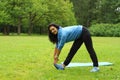 Young beautiful brunette doing an exercise tilt in a summer morning park Royalty Free Stock Photo