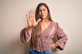 Young beautiful brunette elegant woman with long hair standing over isolated background doing stop sing with palm of the hand Royalty Free Stock Photo