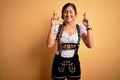 Young beautiful brunette german woman celebrating Octoberfest wearing traditional dress gesturing finger crossed smiling with hope Royalty Free Stock Photo