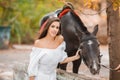 Beautiful young woman in a long white dress with brown horse outdoor. Royalty Free Stock Photo