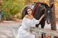 Beautiful young woman in a long white dress with brown horse outdoor. Royalty Free Stock Photo