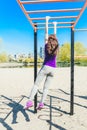 Young beautiful brunette girl in blue t-shirt climbing a horizontal ladder in the park. Royalty Free Stock Photo