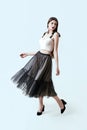 Young beautiful brunette girl in waving dark box pleated midi skirt posing in studio. Woman dancing or making a step.