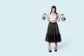 Young beautiful brunette girl in dark box pleated midi skirt posing in studio. Woman balancing holding two disco balls