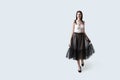 Young beautiful brunette girl in waving dark box pleated midi skirt posing in studio. Woman dancing or making a step.