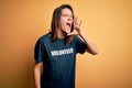 Young beautiful brunette girl doing volunteering wearing t-shirt with volunteer message word shouting and screaming loud to side