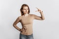 Young beautiful brunette girl frowns and shows small size measure with her hand gesture on a white background