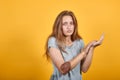 Brunette girl in gray t-shirt over isolated orange background shows emotions Royalty Free Stock Photo