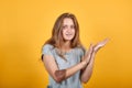 Brunette girl in gray t-shirt over isolated orange background shows emotions Royalty Free Stock Photo