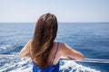 Young beautiful brunette girl sits with her back on a yacht against the backdrop of a beautiful blue sea or ocean Royalty Free Stock Photo