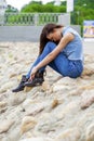 Young beautiful brunette girl sitting on the rocks on the river