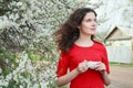 Young beautiful brunette girl with tea cup in arm standing in spring flowering garden Royalty Free Stock Photo