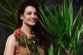 Young beautiful brunette girl in tropical plants over grey background. Royalty Free Stock Photo