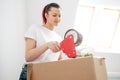 Young beautiful brunette girl in a white t-shirt packs cardboard boxes with a dispenser and adhesive scotch adhesive Royalty Free Stock Photo