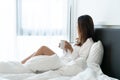 Young beautiful brunette hair woman in white shirt pajamas drinking coffee while sitting on the bed in the morning Royalty Free Stock Photo