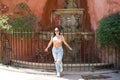 Young and beautiful brunette and latin woman leans on the grille of an old marble fountain in the Jewish quarter of the city of Royalty Free Stock Photo