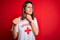 Young beautiful brunette lifeguard girl wearing t-shirt with red cross using whistle Touching painful neck, sore throat for flu,