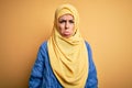 Young beautiful brunette muslim woman wearing arab hijab over isolated yellow background depressed and worry for distress, crying Royalty Free Stock Photo