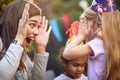 Young beautiful  brunette playing peek a boo with cute little blonde girl at birthday party Royalty Free Stock Photo