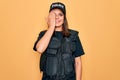 Young beautiful brunette policewoman wearing police uniform bulletproof and cap covering one eye with hand, confident smile on Royalty Free Stock Photo