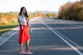 A young beautiful brunette in a red dress hitchhiking and calling on the phone. In the background, the road goes into Royalty Free Stock Photo