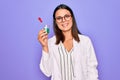 Young beautiful brunette scientist woman wearing coat and glasses holding test tube looking positive and happy standing and Royalty Free Stock Photo