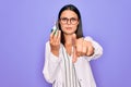 Young beautiful brunette scientist woman wearing coat and glasses holding test tube pointing with finger to the camera and to you, Royalty Free Stock Photo