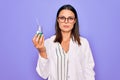 Young beautiful brunette scientist woman wearing coat and glasses holding test tube thinking attitude and sober expression looking Royalty Free Stock Photo