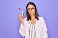 Young beautiful brunette scientist woman wearing coat and glasses holding test tube thinking attitude and sober expression looking Royalty Free Stock Photo