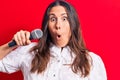 Young Beautiful Brunette Singer Woman Singing Song Using Microphone Over Red Background Scared And Amazed With Open Mouth For