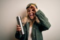 Young beautiful brunette skier woman wearing ski goggles drinking thermo with coffe with happy face smiling doing ok sign with Royalty Free Stock Photo