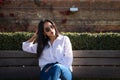 Young, beautiful, brunette, south american woman is sitting on a park bench pensive and sad, she is also depressed and worried. Royalty Free Stock Photo