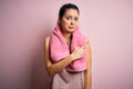Young beautiful brunette sportswoman wearing sportswear and towel over pink background Pointing aside worried and nervous with Royalty Free Stock Photo