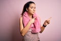 Young beautiful brunette sportswoman wearing sportswear and towel over pink background Pointing aside worried and nervous with Royalty Free Stock Photo